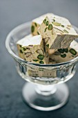 Homemade nougat with pistachios and almonds in a glass bowl