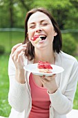 A portrait of s young woman eating strawberry cake