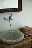 Rustic stone sink integrated into wooden chest of drawers with designer, wall-mounted taps