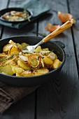 Fried potatoes with onion rings and thyme