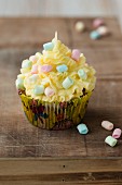 A cupcake decorated with yellow buttercream and mini marshmallows