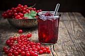 A jar of redcurrant jelly with redcurrants next to it