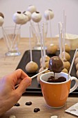 A woman dipping cake pops into chocolate glaze