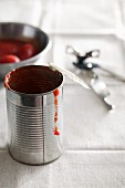 An empty tin of tomatoes with a tin opener