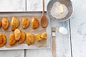 Pierogi on a baking tray with ingredients next to it