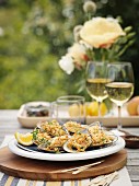 Gratinated oysters and white wine on a garden table