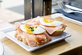 Slices of bread topped with ham and soft-boiled egg