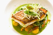 Fried fish tranche on a vegetable salad with a green herb sauce