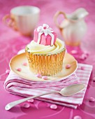 A cupcake decorated with a pink birthday present