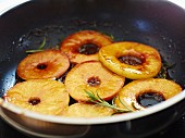 Apple rings being caramelised in a pan