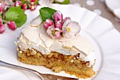 A slice of apple cake topped with meringue and flowers on a plate