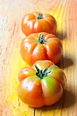 Three Sicilian tomatoes on a wooden surface