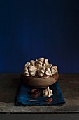 Mini meringues filled with coffee cream in a wooden bowl