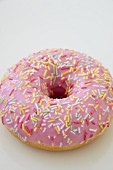 A pink iced doughnut with sugar sprinkles
