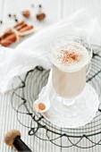 A glass of chai tea latte on a wire rack with whole spices