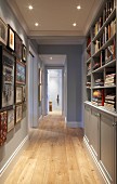 Narrow hallway with fitted cupboards and shelves below suspended ceiling with recessed spotlights in traditional interior