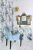 Pale blue velvet armchair at dressing table with valance below vintage three-part mirror on white wooden wall