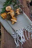 Wild mushrooms and herbs lying on linen napkins with macrame trim