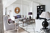 Elegant eingerichtetes Giebelzimmer mit Sofa, Couchtisch, antikem Polstersessel und Tischleuchten