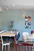 Table and chairs, some with sheepskin rugs, in restaurant with pale wood-clad walls and ceiling