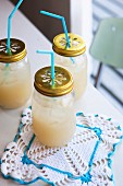 Jars with drinking straws pushed through lids and crocheted doily