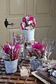 Romantic flower arrangements of deep pink cyclamen, heather and honesty in vases wrapped in birch bark