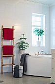 Rustic ladder used as towel rack and small conifer on edge of whirlpool bathtub as festive decoration
