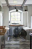 Tabletop on old sewing machine base and pale grey benches below window on platform with chequered floor