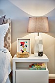 Table lamp with sculptural base on white retro bedside cabinet with bookshelf