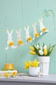 Easter arrangement in pastel shades; garland of paper bunnies, vases of narcissus and tulips