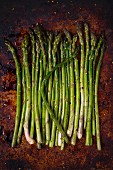 Fresh asparagus with olive oil and spices on a baking tray