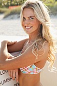 A blonde woman on a beach wearing a checked bikini