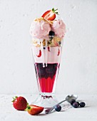 An ice cream sundae with raspberry jelly and fresh berries
