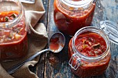 Three jars of vegetable and tomato pasta sauce on a rustic wooden surface