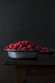 Fresh organic raspberries in a metal bowl on a wooden table