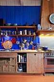 Kitchen counter with solid wooden base units below blue-painted wooden wall