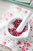 Grinding dried rose petals with sugar using mortar and pestle