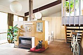 Retro gas heater in wood-clad partition; bicycle at foot of stairs