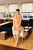 Brunette woman wearing orange jacket and miniskirt in old-fashioned cafe