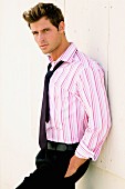 A young man wearing a pink and white striped shirt and black tie