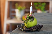 Brennende Kerze in dekorierten Apfel gesteckt