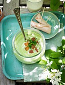 Herb soup with pesto and rolls of ham on a garden table