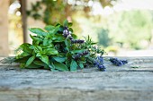 A bunch of fresh herbs with lavender flowers on a wooden table