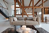 Offenes Wohnzimmer mit sichtbaren Holzbalken und modernen Möbeln