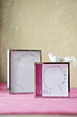 Hand-drawn silhouettes in chrome picture frames and bird ornament