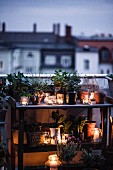 Potting bench atmospherically decorated with plants and candle lanterns on roof terrace at twilight