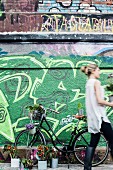 Mit Pflanzen dekoriertes Fahrrad vor mit Graffiti besprühter Wand