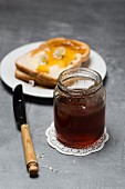 A jar of honey with slices of toast with honey and daisies behind it
