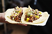 A hand holding a paper plate of tacos (Barcelona, Spain)