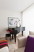 Blick über Sessel auf schwarzen Klavierflügel in Zimmerecke, Fenster mit bodenlanger weißer Gardine